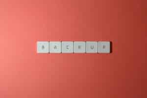 Free Close-up of keyboard keys spelling 'BACKUP' placed on a coral-colored surface. Stock Photo