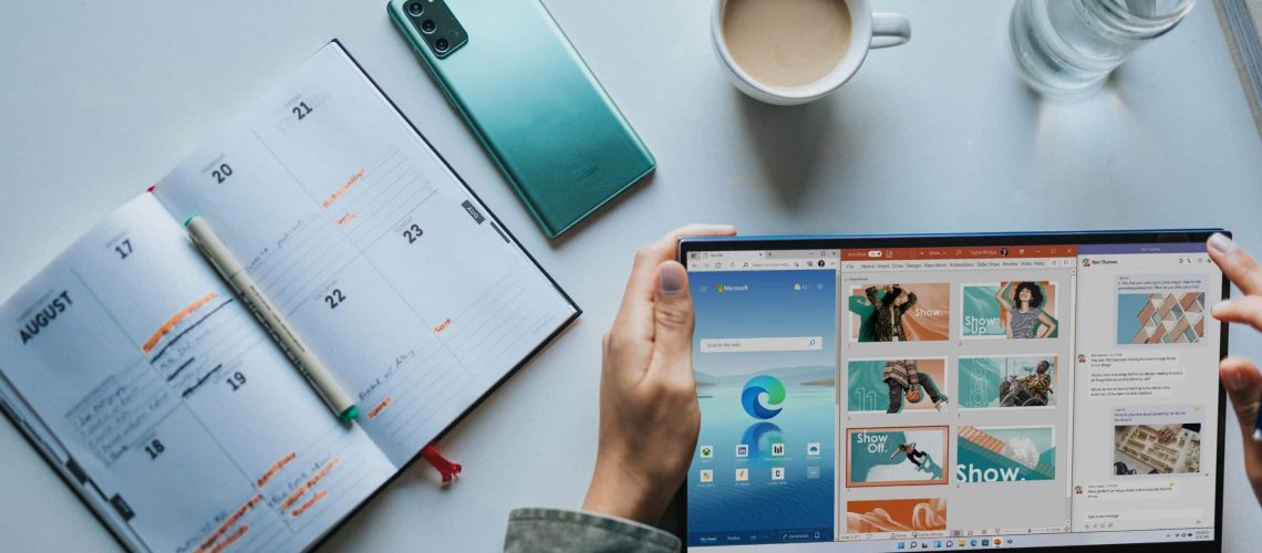 person using Windows 11 computer beside white ceramic mug on white table