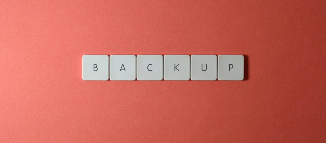 Free Close-up of keyboard keys spelling 'BACKUP' placed on a coral-colored surface. Stock Photo